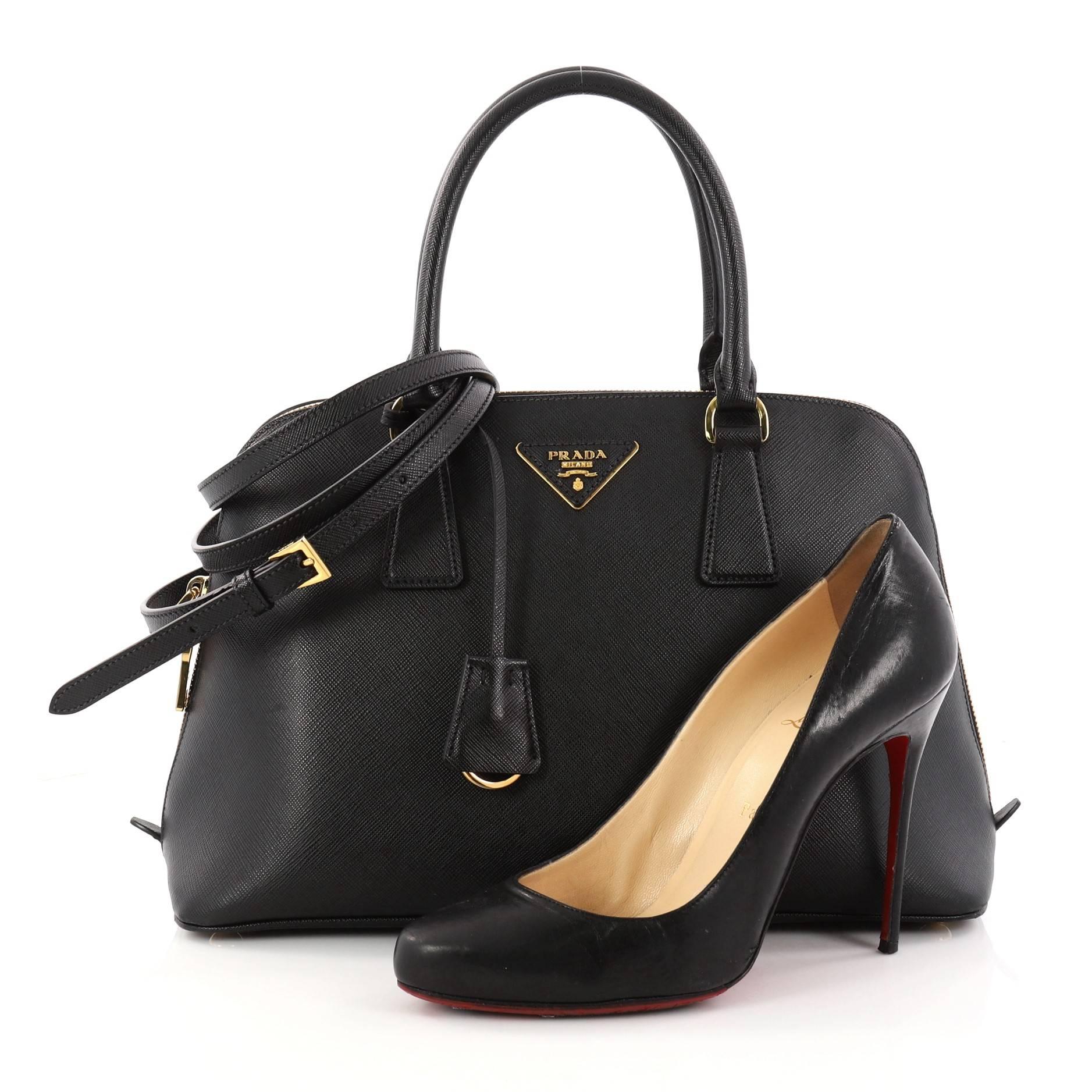 This authentic Prada Promenade Handbag Saffiano Leather Medium is elegant in its simplicity and structure. Crafted in black saffiano leather, this sleek dome-shaped satchel features dual-rolled handles, protective base studs, Prada logo at the