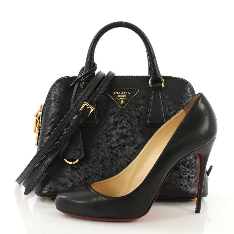 This Prada Promenade Handbag Saffiano Leather Small, crafted from black saffiano leather, features dual rolled handles, triangle Prada logo, and gold-tone hardware. Its two-way zip closure opens to a black fabric interior with a center zip