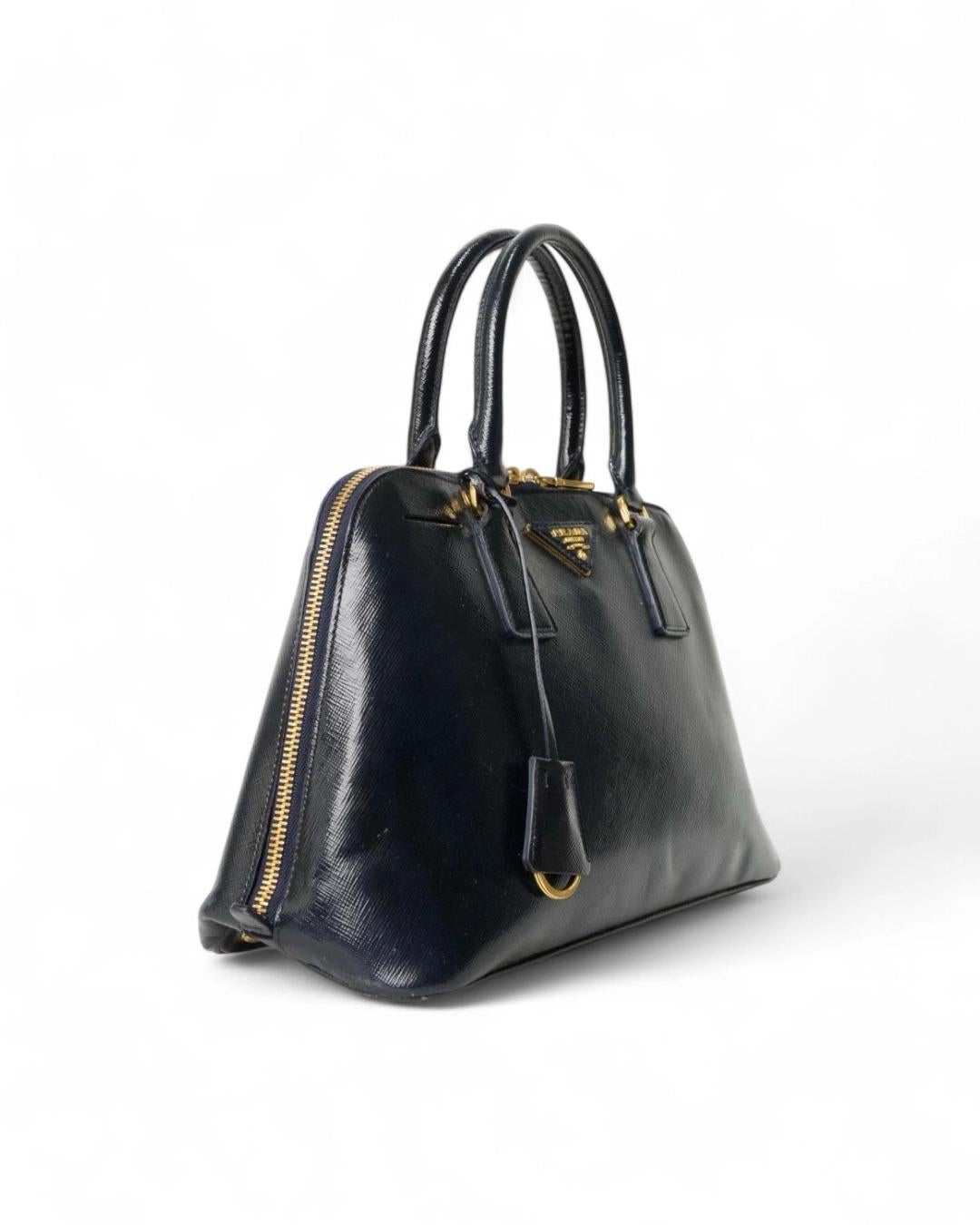 Borsa firmata Prada, modello Promenade Tote, misura Medium, realizzata in pelle Saffiano nella colorazione blu con hardware dorato. Dotata di una chiusura semi circolare a doppio cursore, internamente rivestita in tela logata tono su tono con