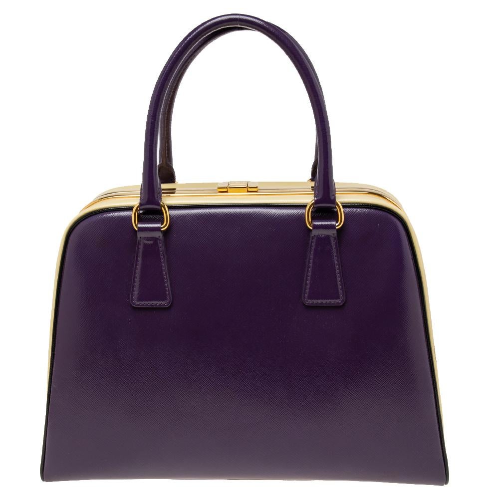 Giving handle bags an elegant update, this Pyramid Frame bag by Prada will be a valuable addition to your closet. It has been crafted from Saffiano leather and styled with gold-toned hardware. It comes with dual top handles, protective metal feet at