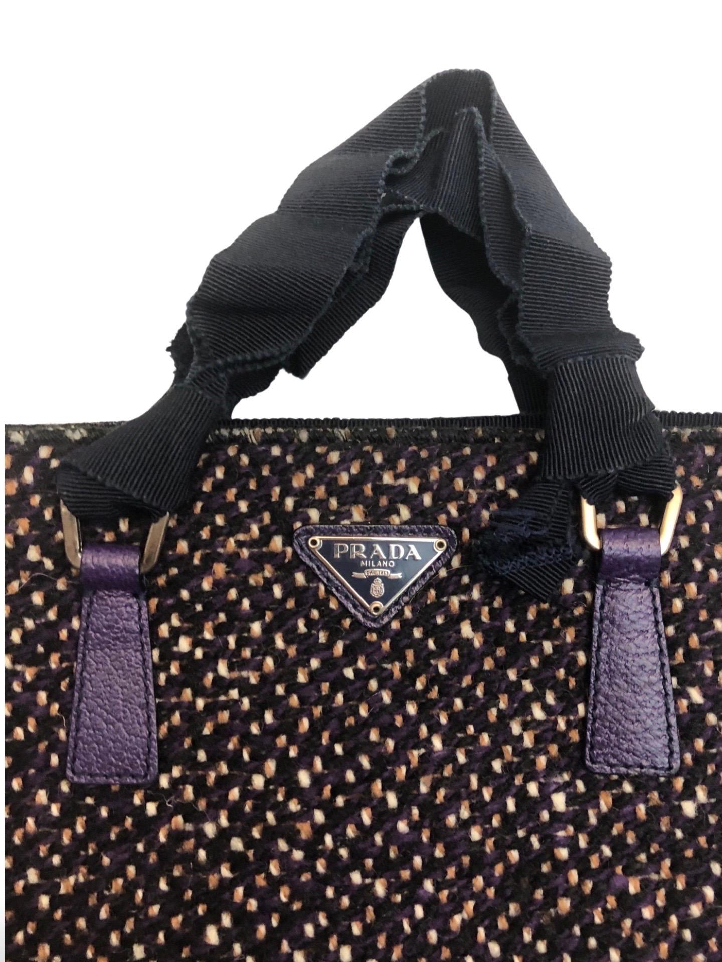 - Purple leather and wool tweed mixed tote bag is rarely seen to be made in Prada collection. The bag in excellent to mint condition. 

- Purple leather zip closure. 

- Nylon material handle. 

- Back zip pocket closure. 

- Iconic Prada logo. 

-