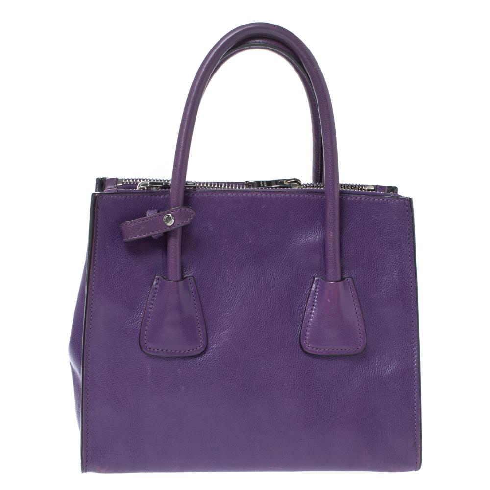 This lovely tote from Prada is crafted from leather and features a purple shade. It flaunts dual round handles, protective metal feet, and a spacious nylon-lined interior. Perfect to complement most of your outfits, this bag is worth every cent and