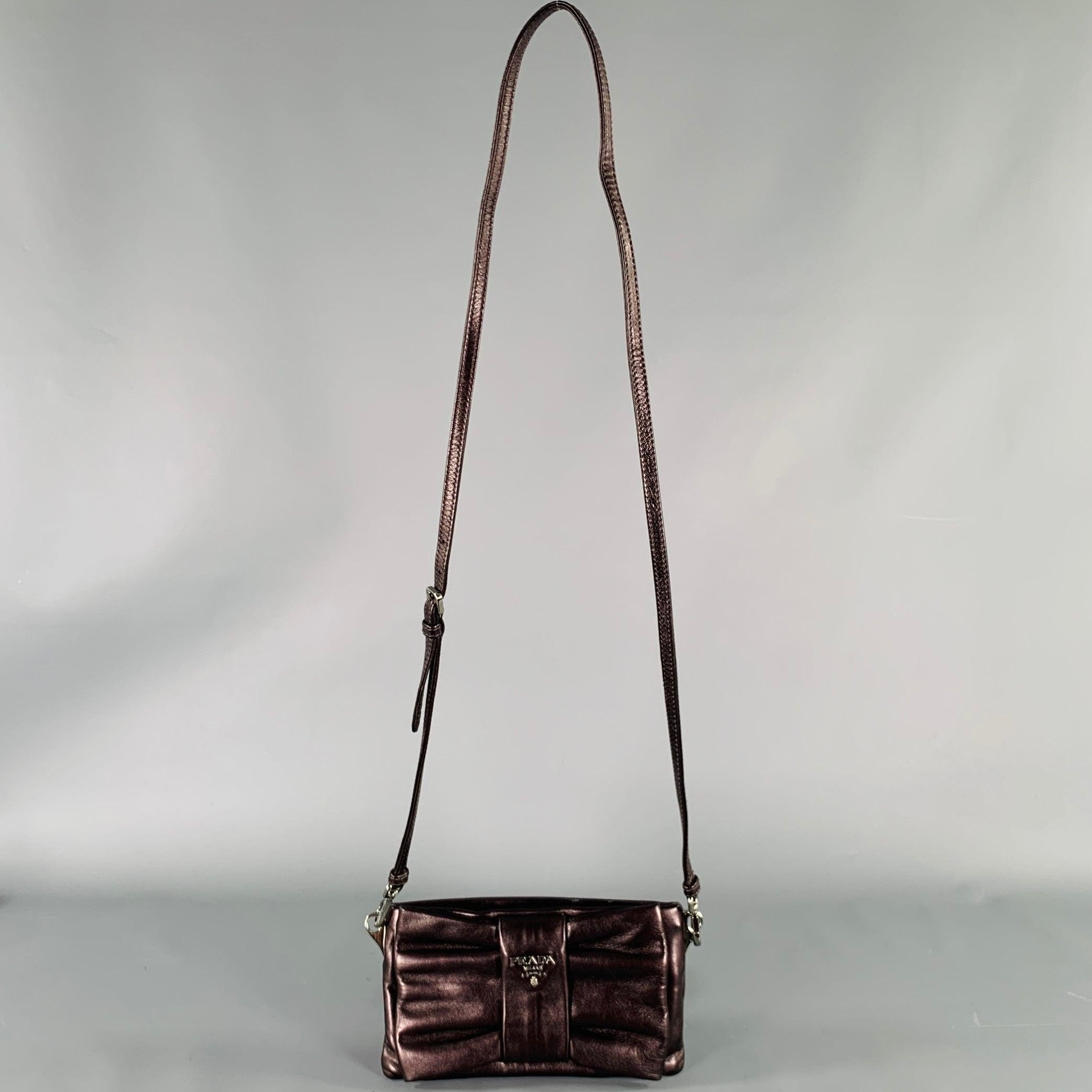 PRADA handbag
in a shimmery purple leather featuring a rectangular bow shape, removable crossbody shoulder strap, and zip closure. Made in Italy.Very Good Pre-Owned Condition. Minor marks. 

Measurements: 
  Length: 7.75 inches Height: 4.25 inches