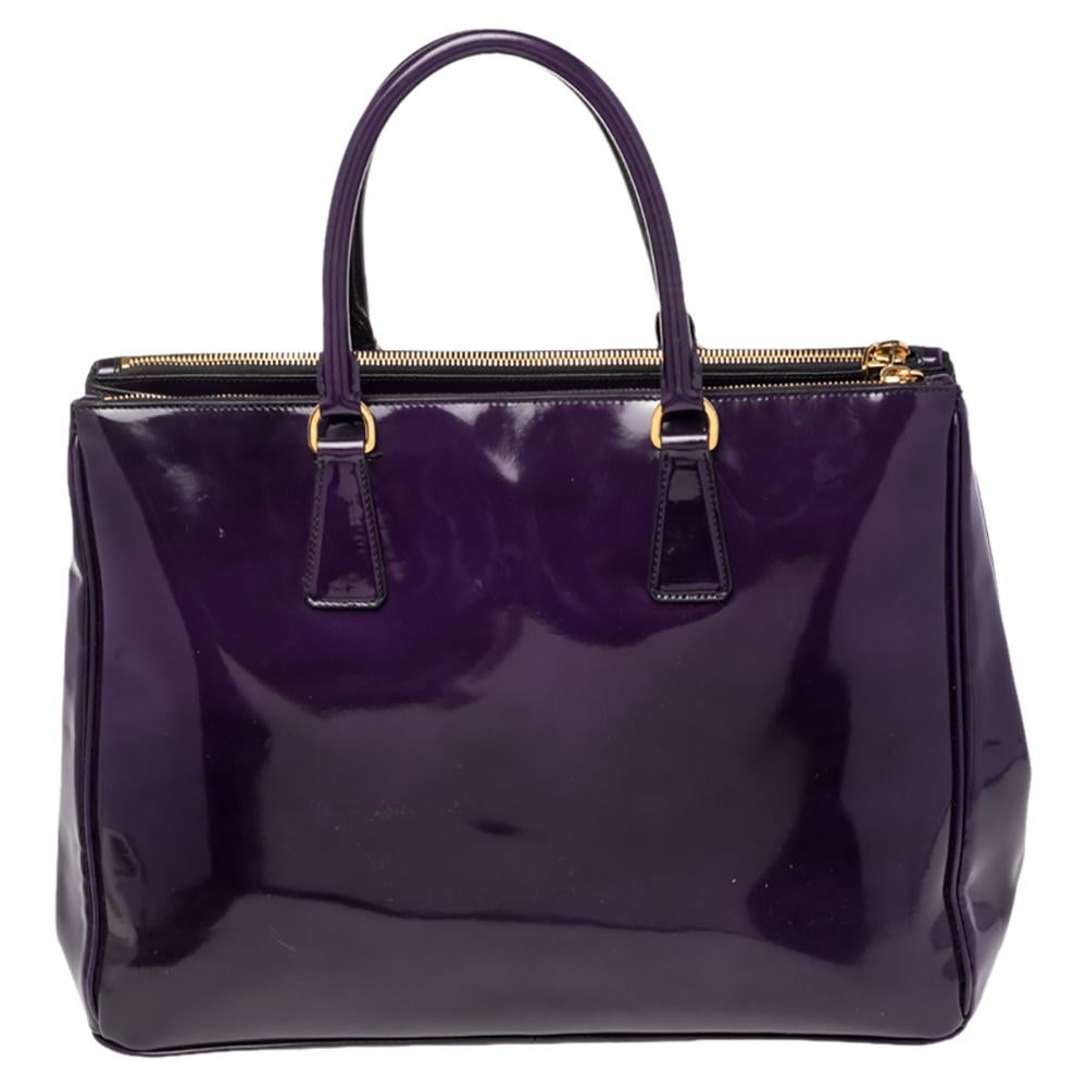 Loved for its classic appeal and functional design, Galleria is one of the most iconic and popular bags from the house of Prada. This beauty in purple is crafted from Spazzolato leather and is equipped with two top handles, the triangular brand logo