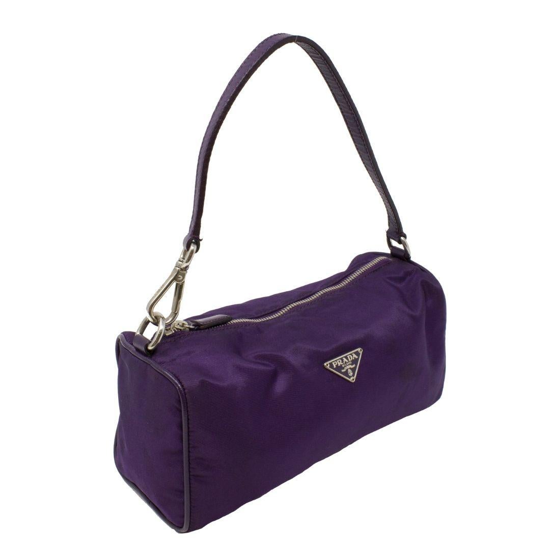 Super trendy purple Prada pochette with the perfect shoulder strap drop. Crafted in tessuto nylon with the signature tonal logo plate, silver-tone hardware, a flat purple durable leather handle, and purple leather trimming. The tonal leather zipper