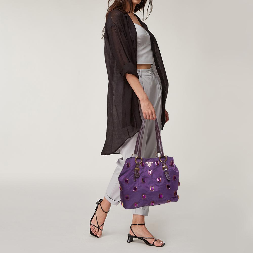 The house of Givenchy has exclusively crafted this elegant bag for you. Complement your attire by adorning this classic bag in purple. It is made from Tessuto fabric and features jewel embellishments all over along with twin top handles and the