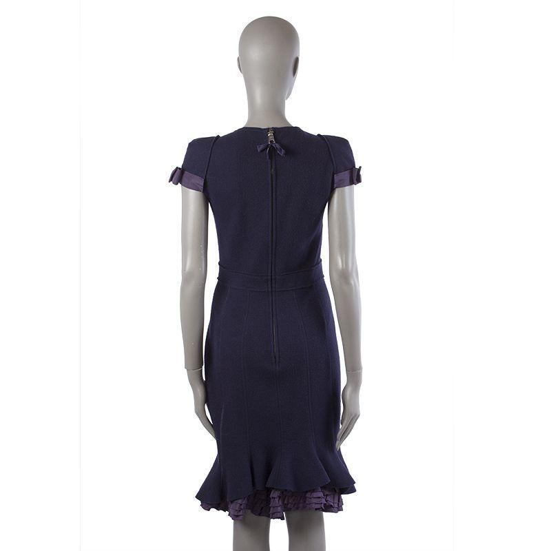 Prada trumpet dress in dark purple virgin wool (100%). With cap-sleeves, bow detail on each sleeve, sweetheart neckline, and small ruffles sticking out from the back. Closes with back zipper. Lined in midnight blue silk (56%) and polyester (44%).