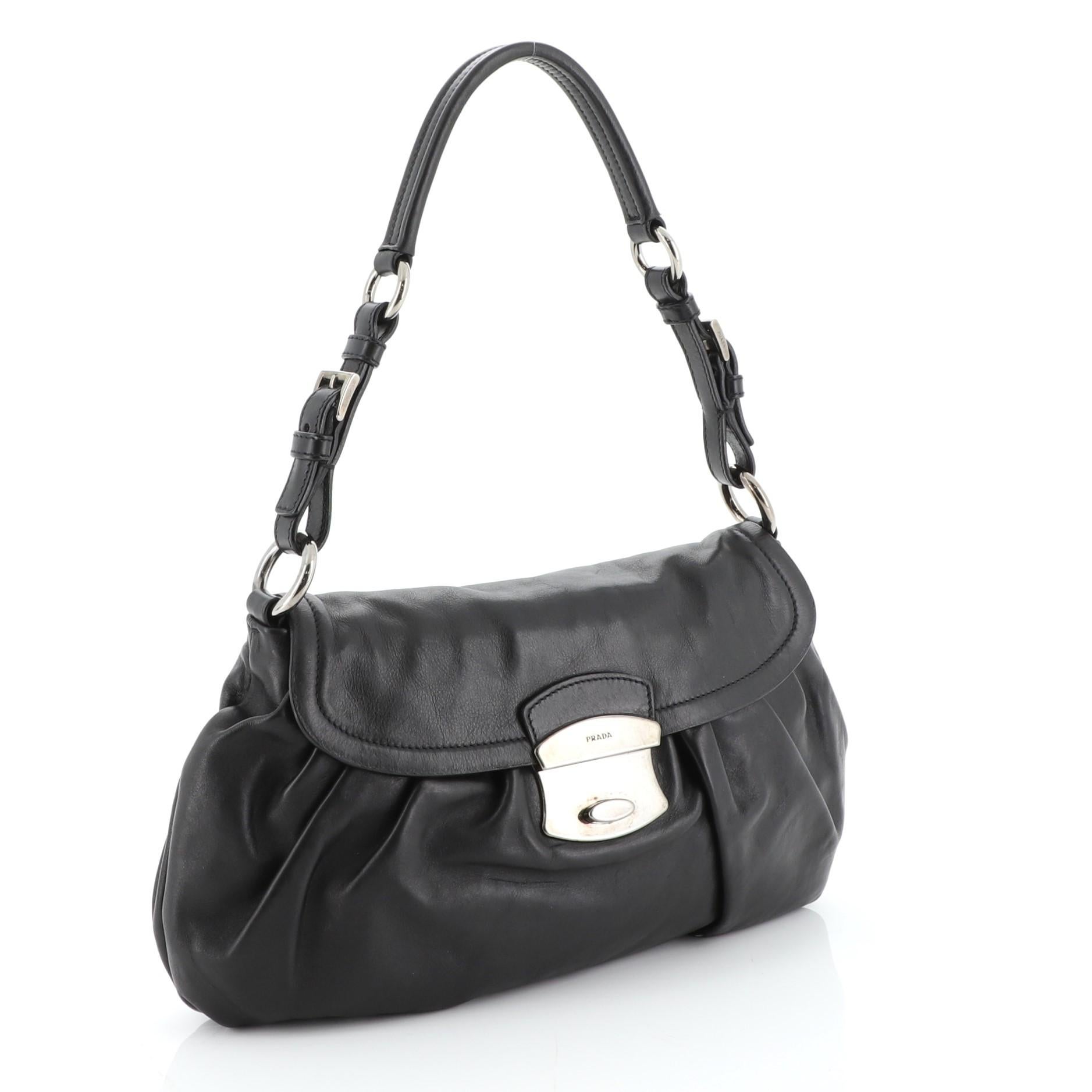 This Prada Pushlock Shoulder Bag Soft Calfskin Medium, crafted in black soft calfskin leather, features leather top shoulder strap and gunmetal-tone hardware. Its push-lock closure opens to a black fabric interior with side zip pocket.

Condition: