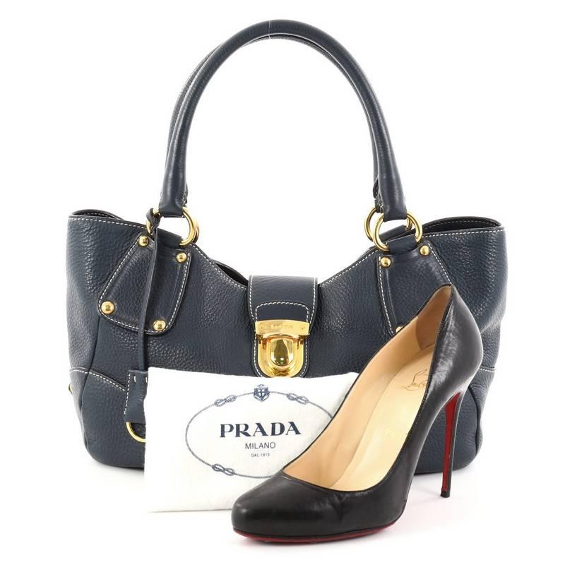 This authentic Prada Pushlock Tote Vitello Daino Medium is the ideal bag for everyday use and light traveling. Constructed from blue vitello daino leather, this simple tote features dual-rolled leather handles, protective base studs, and accented
