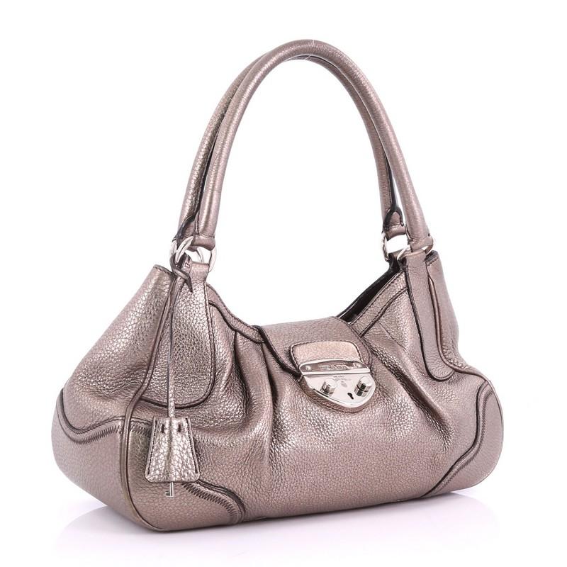 This Prada Pushlock Tote Vitello Daino Medium, crafted in Pewter vitello daino leather, features dual rolled leather handles and silver-tone hardware. Its top push-lock closure opens to a brown fabric interior with zip and slip pockets. **Note: Shoe