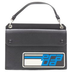 PRADA Racing Graphic Logo sac à main en saffiano noir avec rabat et pochette plate sur le devant
