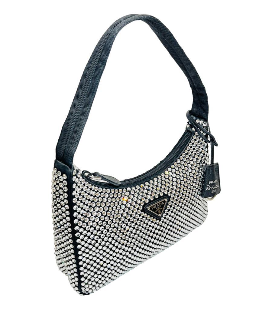 Prada Re-Edition 2000 Satin & Crystal Mini Bag

Iconic mini hobo bag crafted from luxurious satin and studded with crystals.

Detailed with emblematic enamel triangle logo to the centre.

Featuring black leather clochette with 'Prada Re-Edition