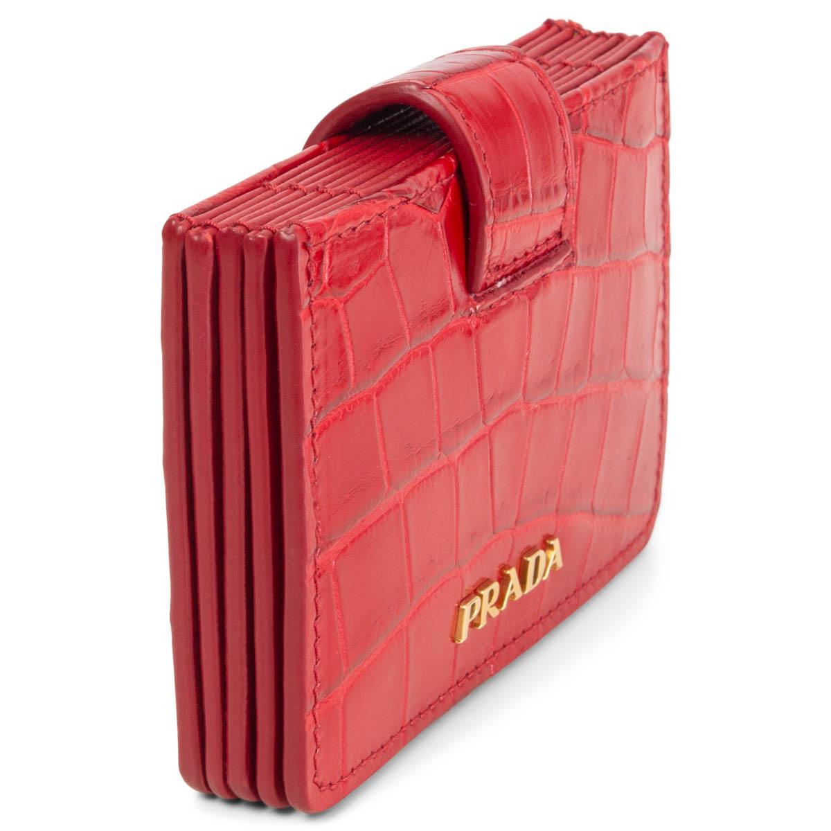 100% authentic Prada Accordion credit card wallet in red crocodile leather featuring gold-tone logo hardware and with 5 credit card slots, but they fit more than just one card. Has been carried and is in excellent condition.
