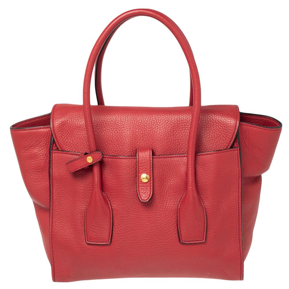 Incredibly stylish and high on functionality, this Prada tote will be the perfect pal for your daily errands! It has been crafted from red leather and designed with a gold-tone lock on the front. It flaunts dual top handles and opens to a
