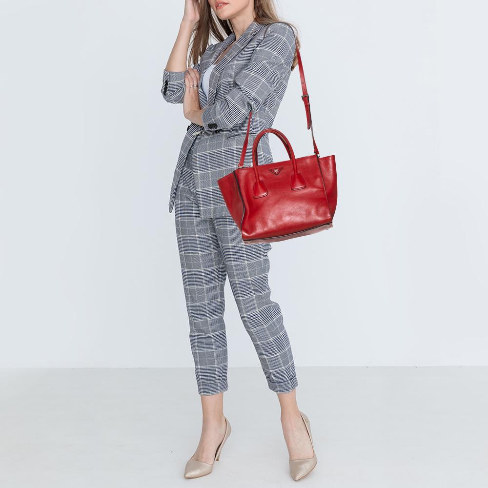 Add some effortless style and luxury to your everyday looks with this stunning Prada tote. Crafted in red-hued leather, this bag can store all that you need through the day or for work in its large middle compartment and two zippered compartments.