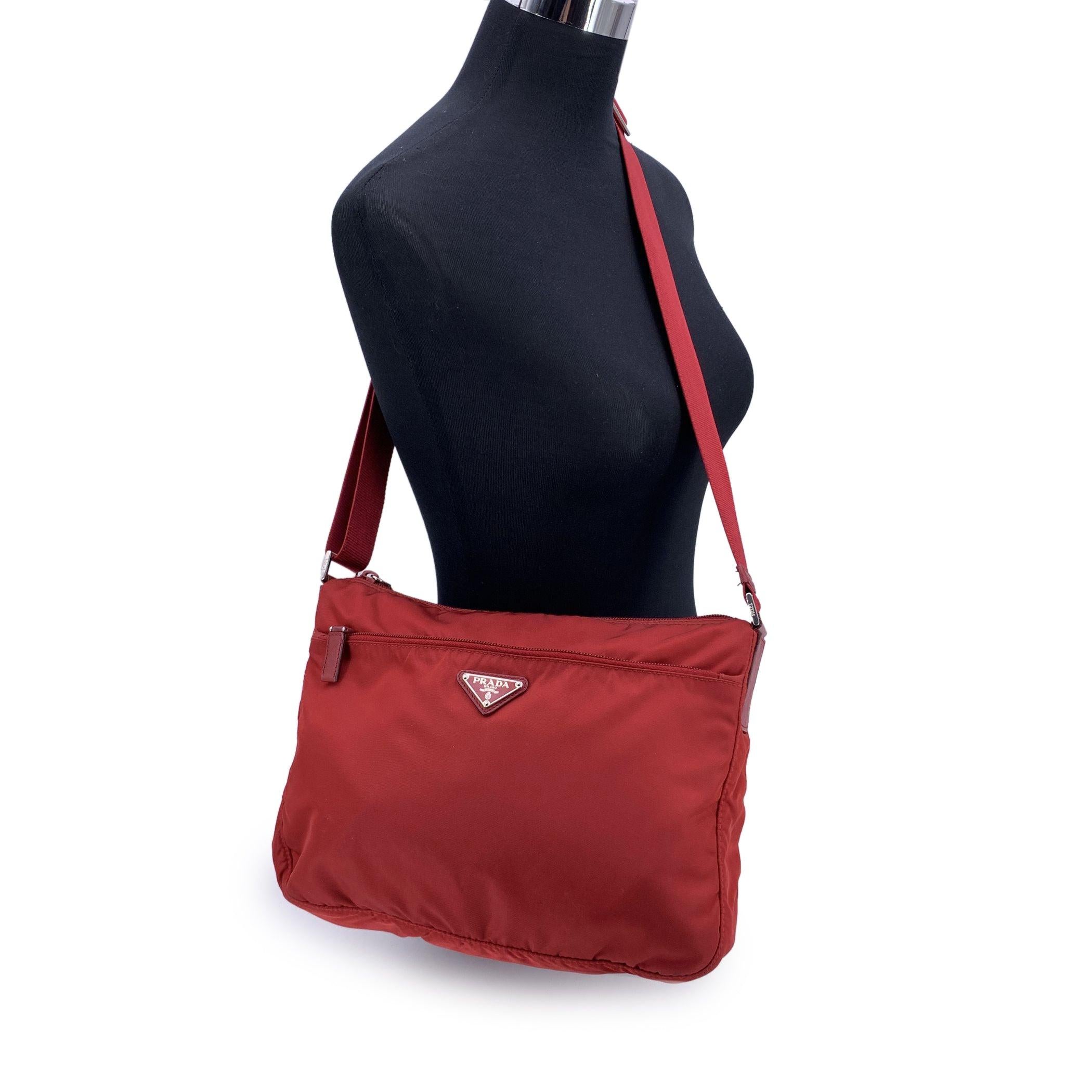 Embrace the perfect blend of functionality and luxury with this PRADA Messenger Bag-a sleek and stylish piece that exudes understated elegance. Crafted in durable red tessuto nylon canvas, this bag is accented with red leather trim, offering a