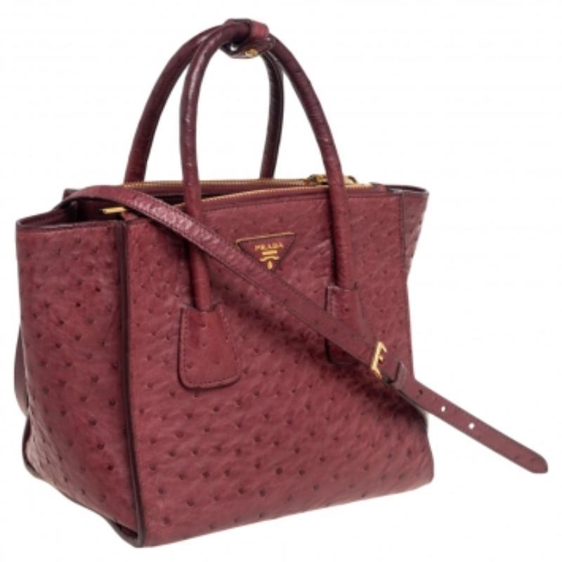 Add timeless style and luxury to your look with this stunning Prada Twin tote. Crafted in red ostrich leather, this bag can store all that you need in its spacious interior. The tote is detailed with the brand logo on the front, held by dual