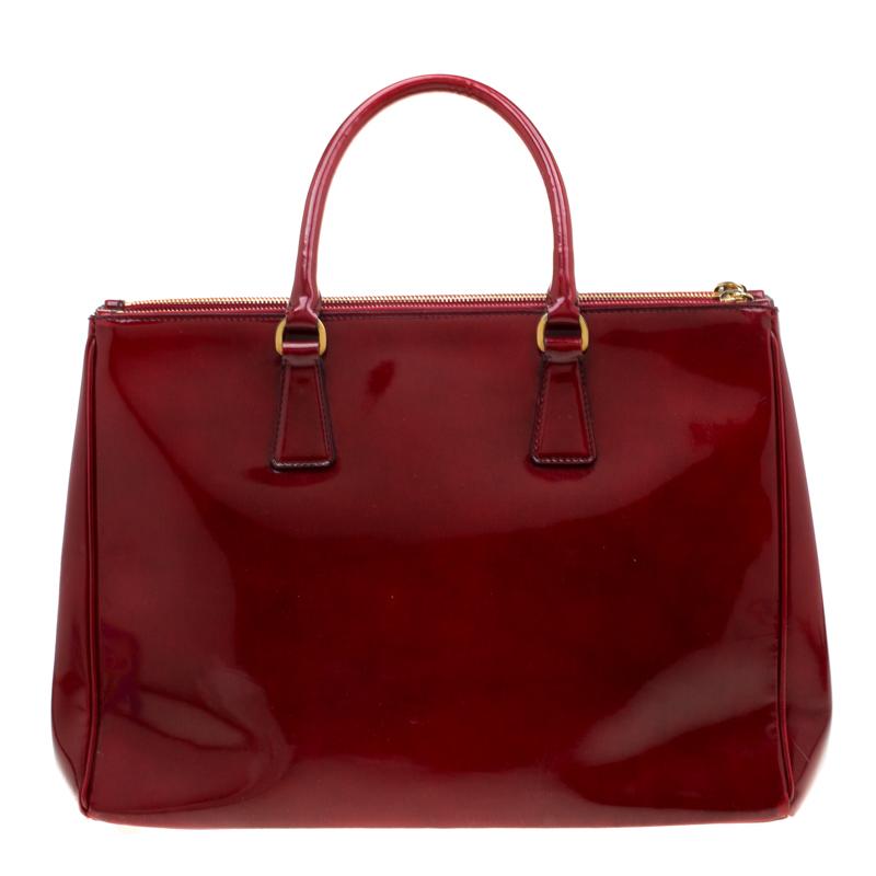 Feminine in shape and grand on design, this Double Zip tote by Prada will be a loved addition to your closet. It has been crafted from patent leather and styled minimally with gold-tone hardware. It comes with two top handles, two zip compartments
