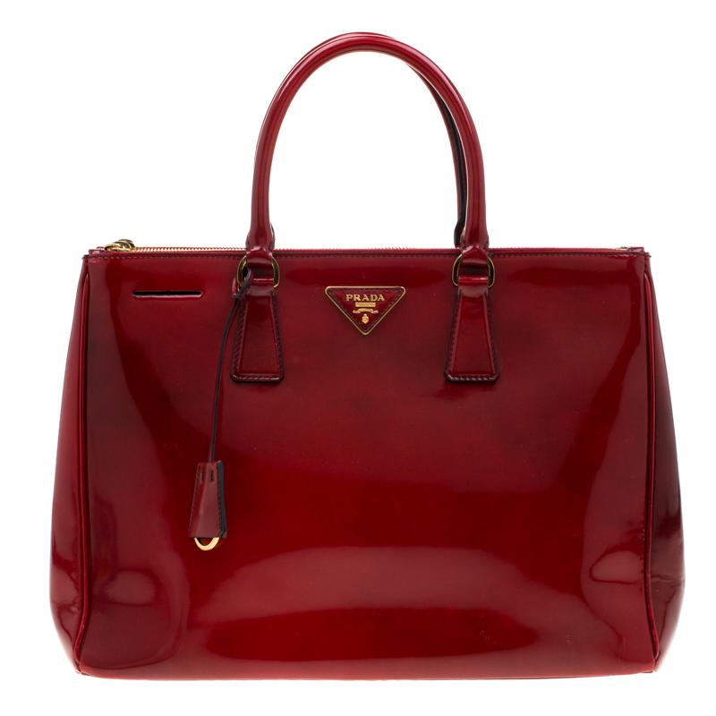 Feminine in shape and grand on design, this Double Zip tote by Prada will be a loved addition to your closet. It has been crafted from patent leather and styled minimally with gold-tone hardware. It comes with two top handles, two zip compartments