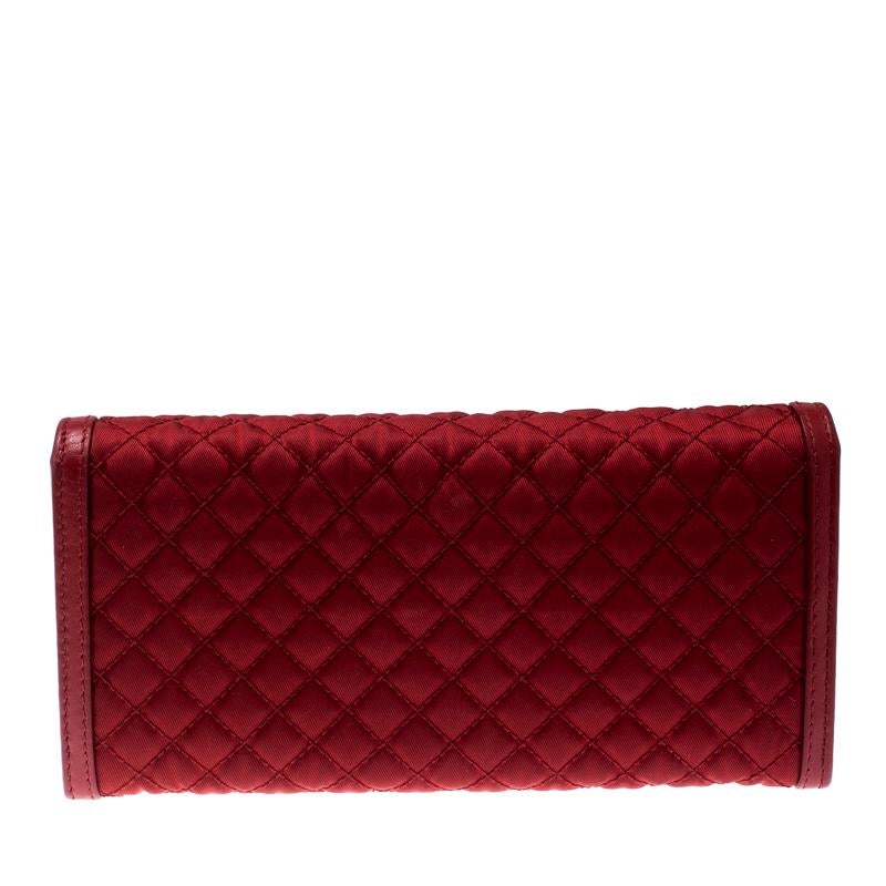 Carry this spacious and functional quilted leather wallet by Prada everywhere. Crafted from red nylon and leather, this flap front wallet is accented with a gold-tone Prada logo lettering. The easy to organize interior features multiple credit card