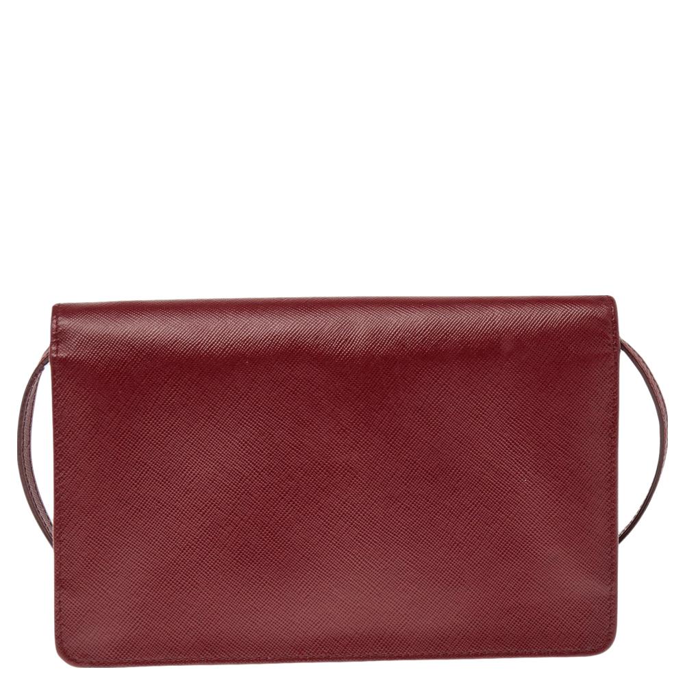 This crossbody bag from Prada is crafted from red Saffiano leather and is held by an adjustable shoulder strap. The bag features a gold-tone brand logo detailing on the front flap and a leather interior housing a zip pocket.

