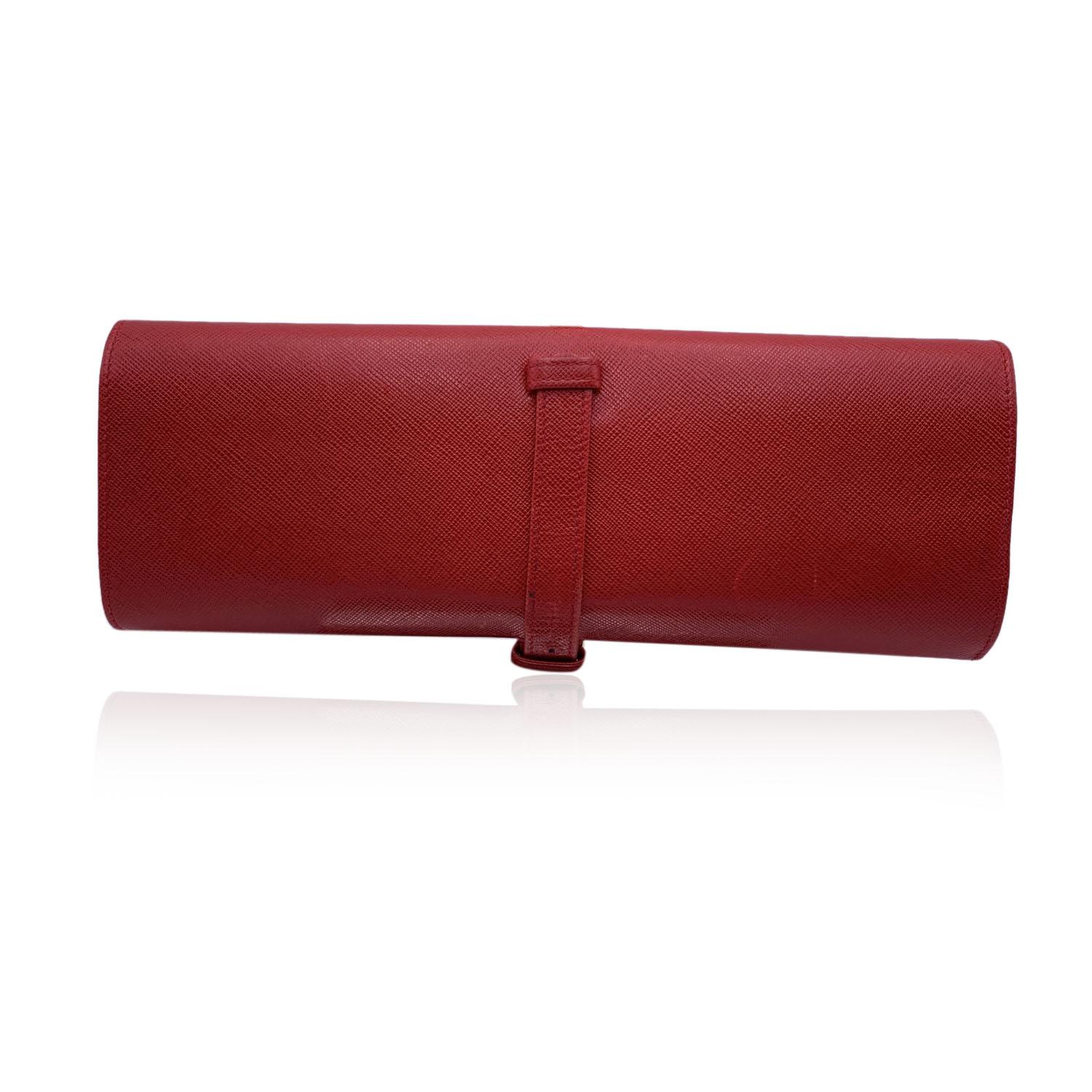 Prada jewelry case crafted in red saffiano leather. It will keep your fine jewelry organized and safe while on the go. A perfect travel companion that with tuck nicely into your carry on or handbag. 'Prada' triangle logo on the front. Buckle