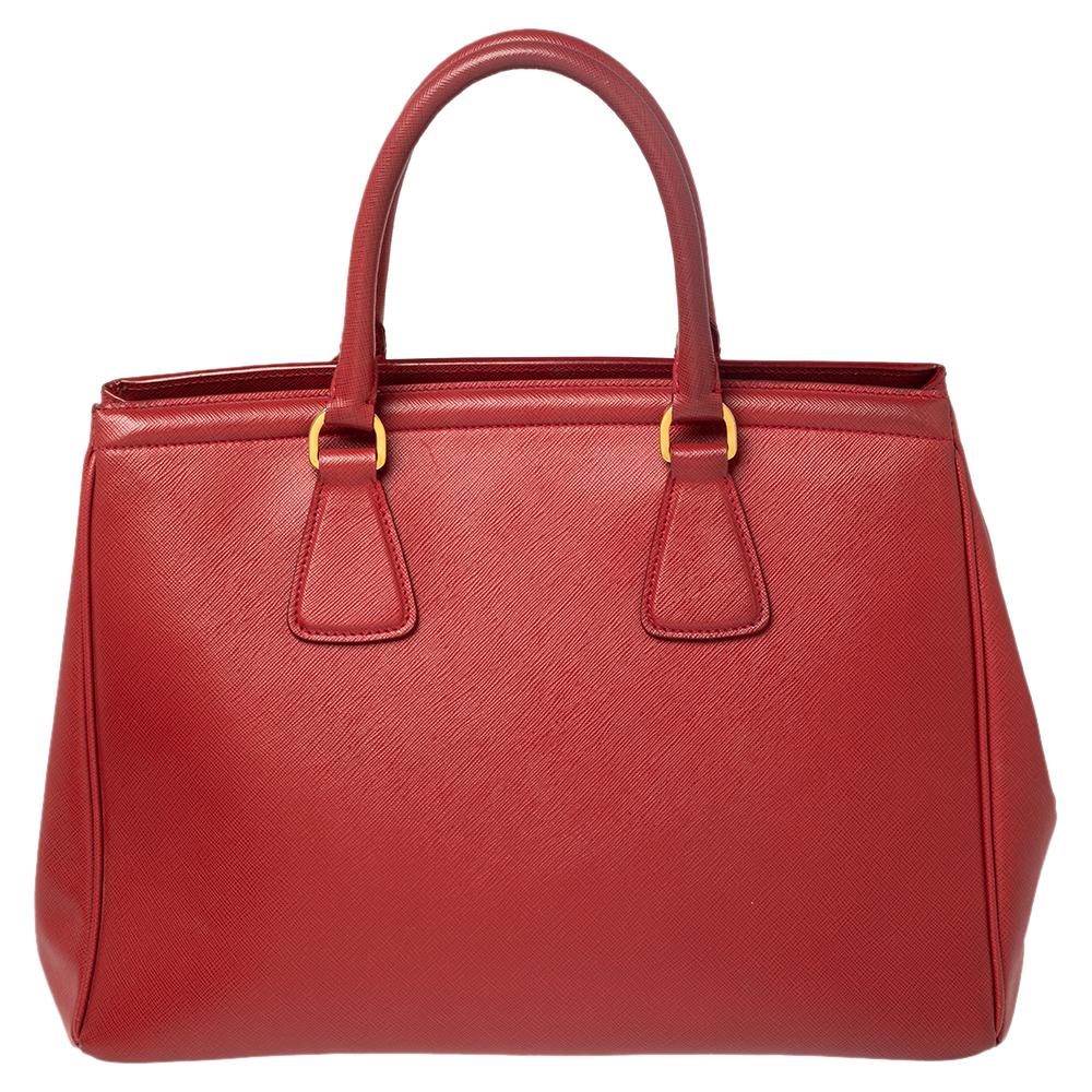 Masterfully created, this Prada Parabole tote is a structured beauty. Designed in a Saffiano leather body, it exudes style and class in equal measures. This delightful red piece is held by two top handles and equipped with a spacious interior.