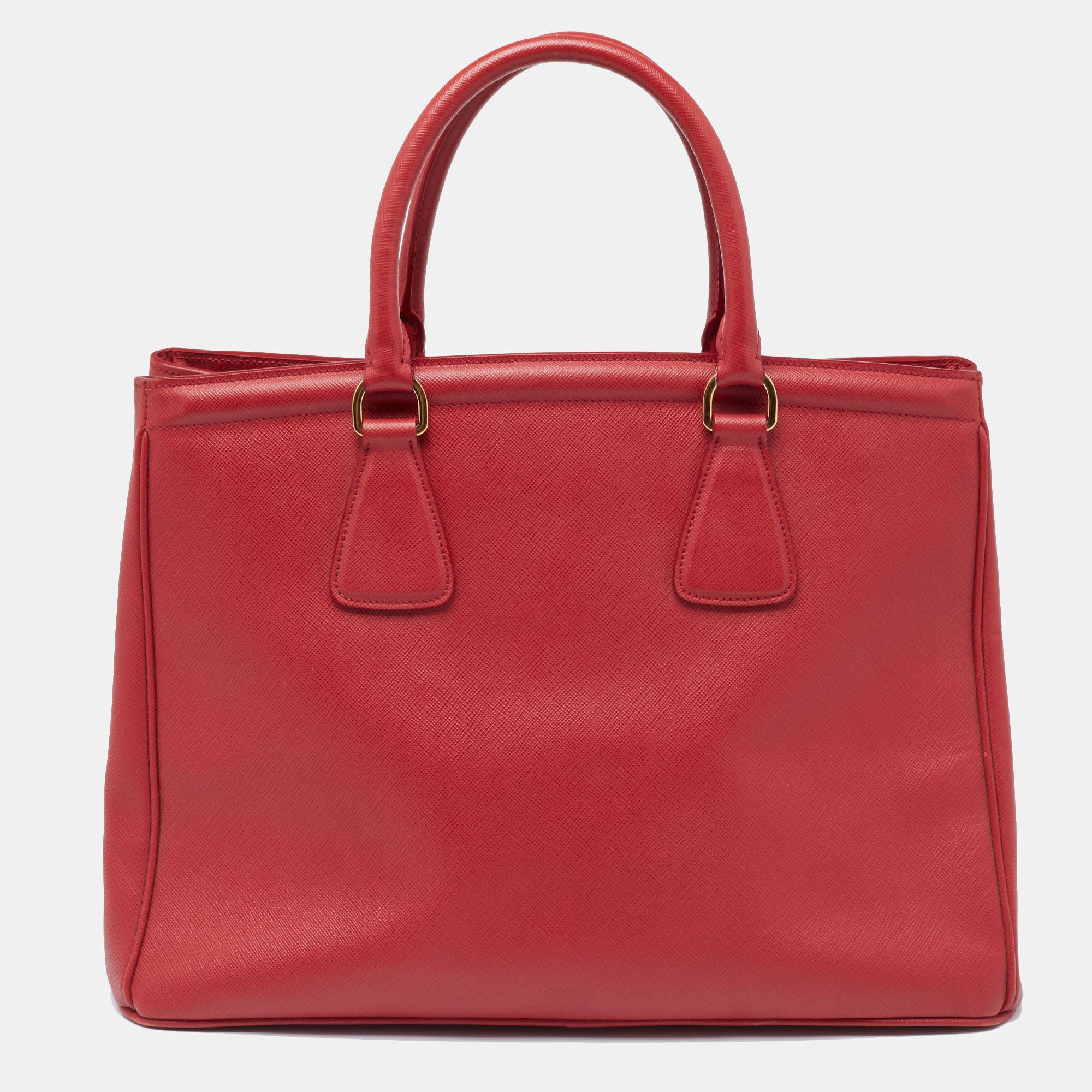 This ever-classy Parabole tote from Prada is crafted from Saffiano leather. The tote has a red exterior featuring dual handles, a leather tag, and protective metal feet at the bottom. The fabric-lined interior is added with pockets.

Includes: