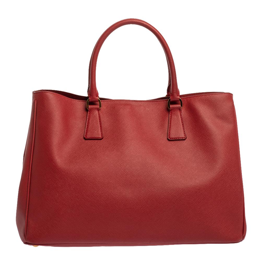 High in appeal and style, this tote is a Prada creation. It has been crafted from leather and shaped to exude class and luxury. The bag comes with two handles and a spacious nylon interior for your ease. Protective metal feet and the brand logo on