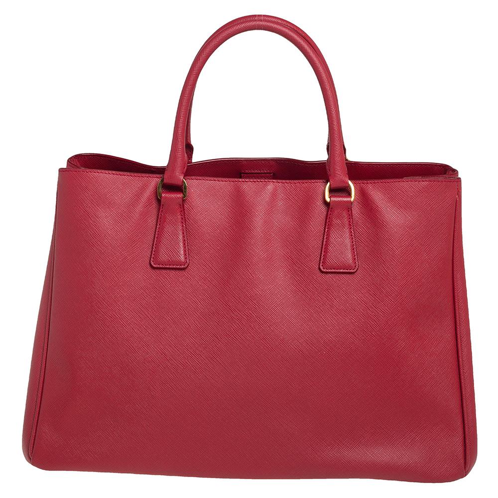 High in appeal and style, this tote is a Prada creation. It has been crafted from Saffiano leather and shaped to exude class and luxury. The bag comes with two handles and a spacious nylon interior for your ease. Protective metal feet and the brand