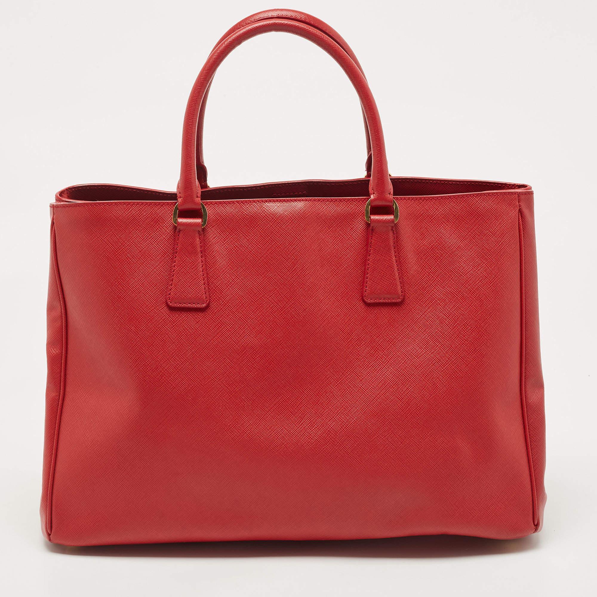 The Prada Gardener's tote exudes sophistication and practicality. Crafted from luxurious saffiano leather, this spacious tote features a vibrant red hue that adds a bold statement to any outfit. With its ample storage capacity and sturdy