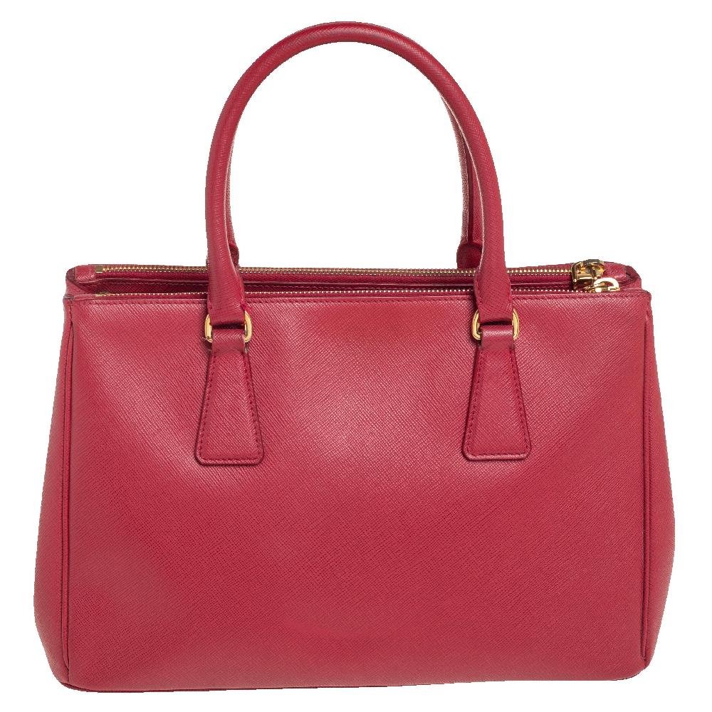 Loved for its classic appeal and functional design, Galleria is one of the most iconic and popular bags from the house of Prada. This beauty in red is crafted from Saffiano Lux leather and is equipped with two top handles, the brand logo at the