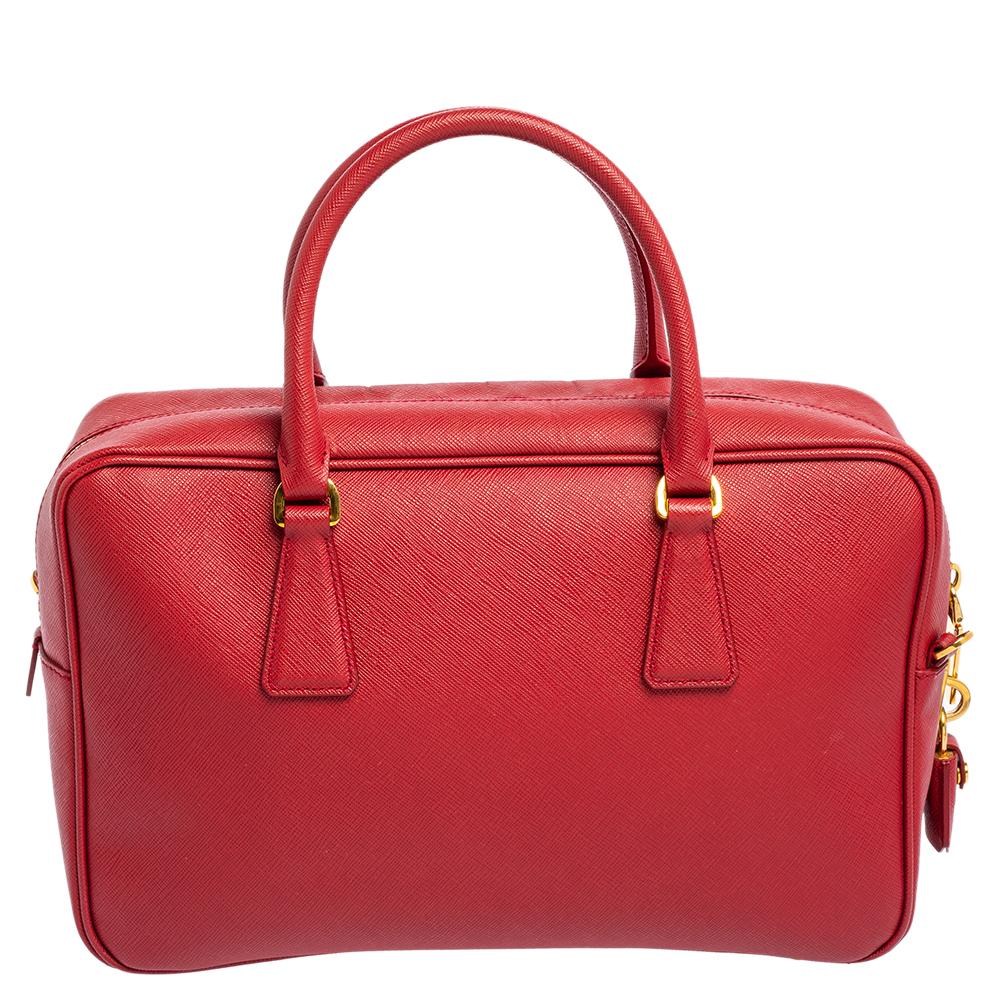 Diese elegante Bauletto Tasche von Prada ist aus Saffiano Lux Leder gefertigt und eignet sich perfekt für den täglichen Gebrauch. Die schöne Tasche verfügt über Details in Form von goldfarbenen Beschlägen, zwei Griffen an der Oberseite, einem