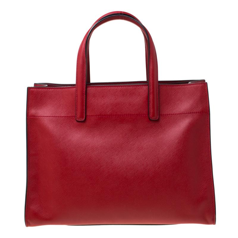 Handbags can transform any outfit, just like this classy tote from the house of Prada can. Crafted from soft Saffiano leather and lined with nylon and leather on the insides, it features two flat handles, and a spacious interior divided by a zip