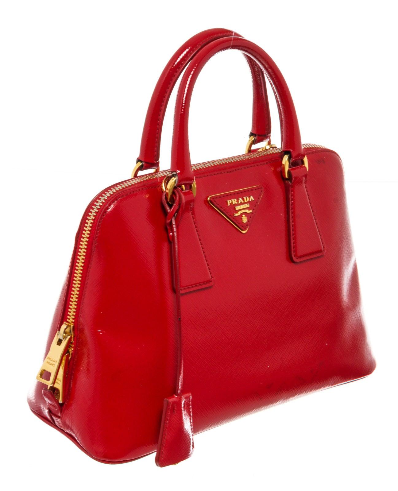 Prada Top Handle bag is made of gorgeous sleek red glossy Saffiano Vernice patent leather with bold gold-tone hardware. This top handle bag features a zip around closure and a spacious interior with several compartments and red jacquard canvas