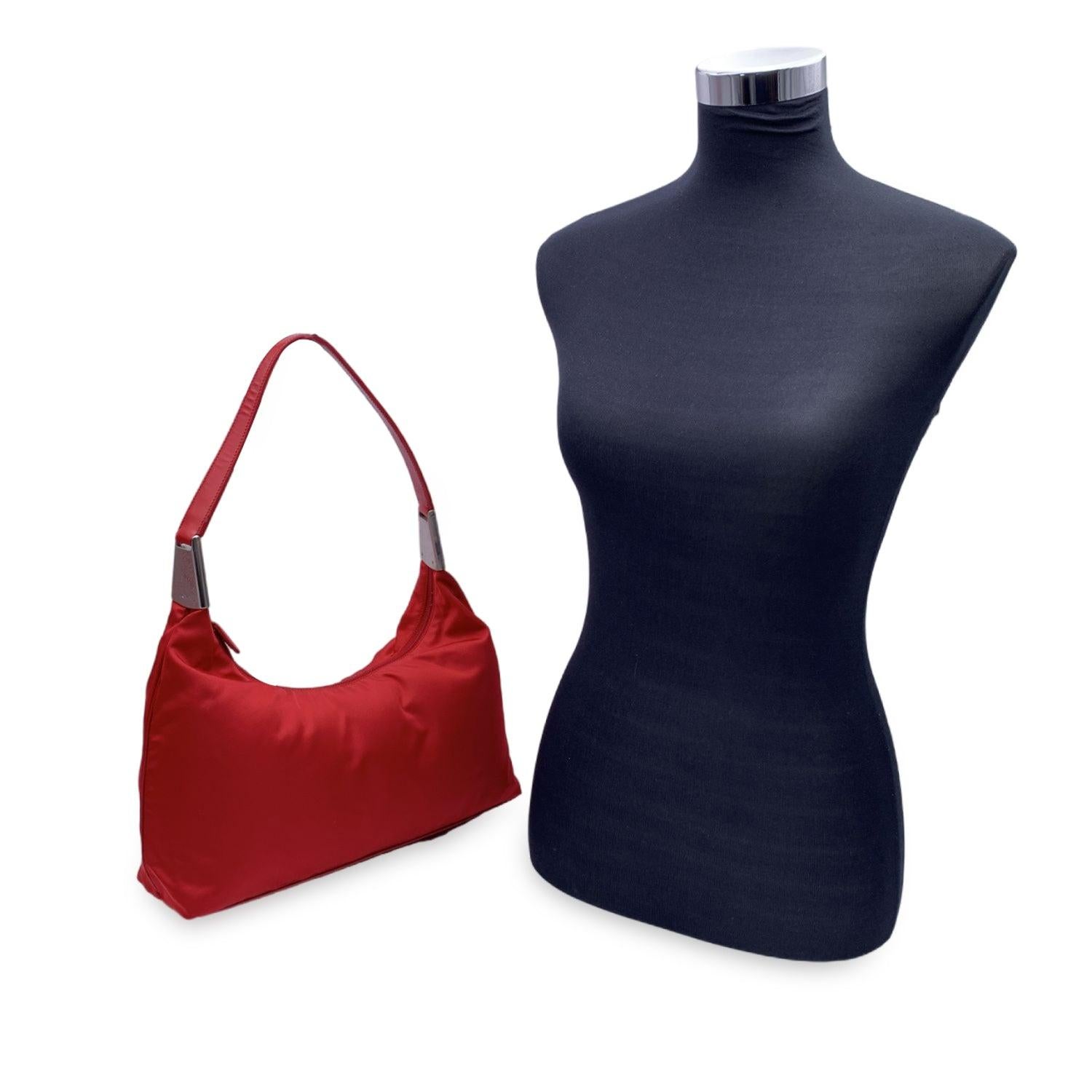 Atrevido, sencillo e inconfundiblemente Prada: este bolso bandolera Hobo vintage captura la esencia del minimalismo de principios de la década de 2000 con un toque de rojo intenso. Fabricado con la lona de nailon tessuto característica de la marca,