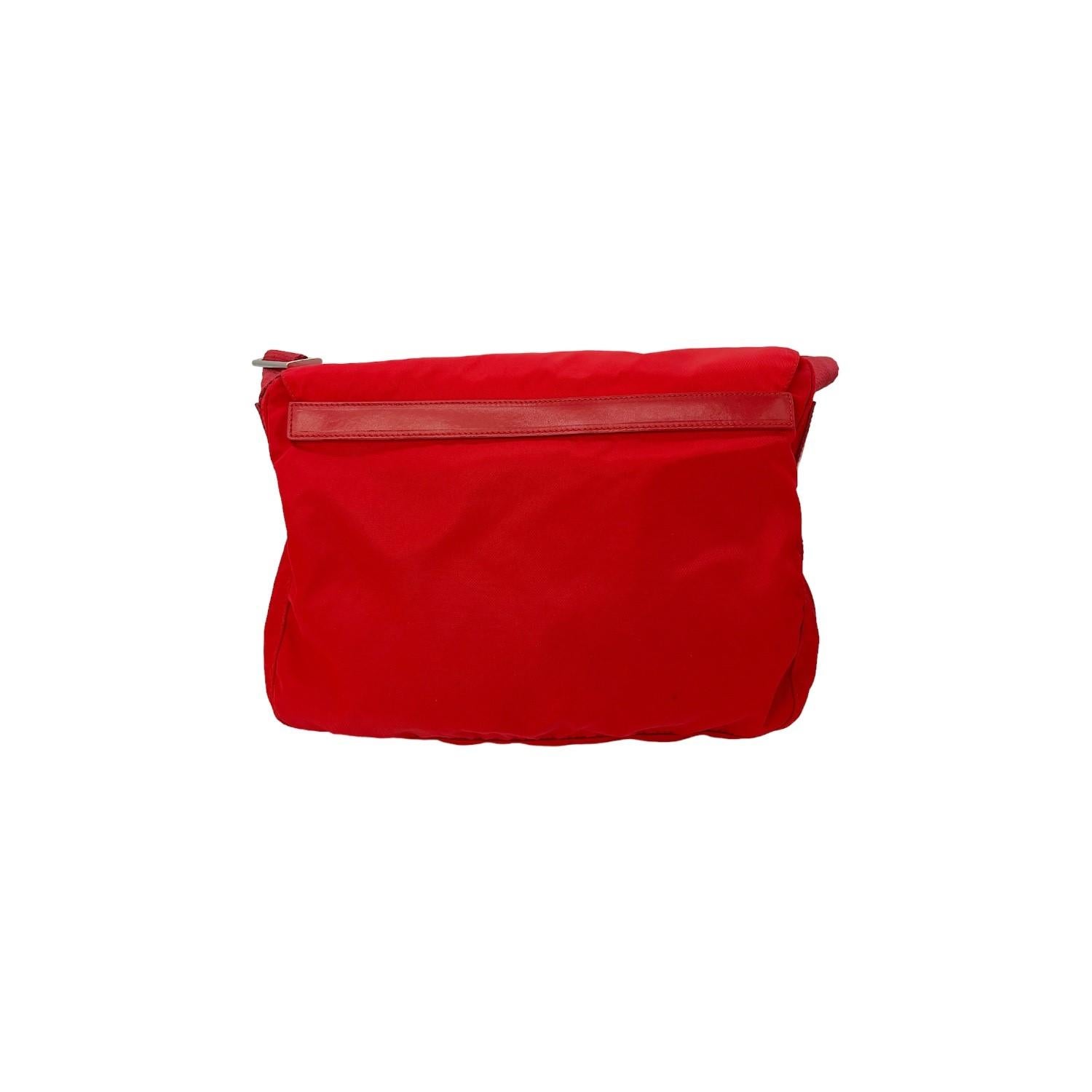 Questa borsa Prada Tessuto Messenger è stata realizzata in Italia ed è composta da un esterno in nylon rosso e da elementi hardware in tonalità argento. Ha 2 tasche frontali con cerniera e una chiusura a libro con fibbia e cerniera che si apre su un