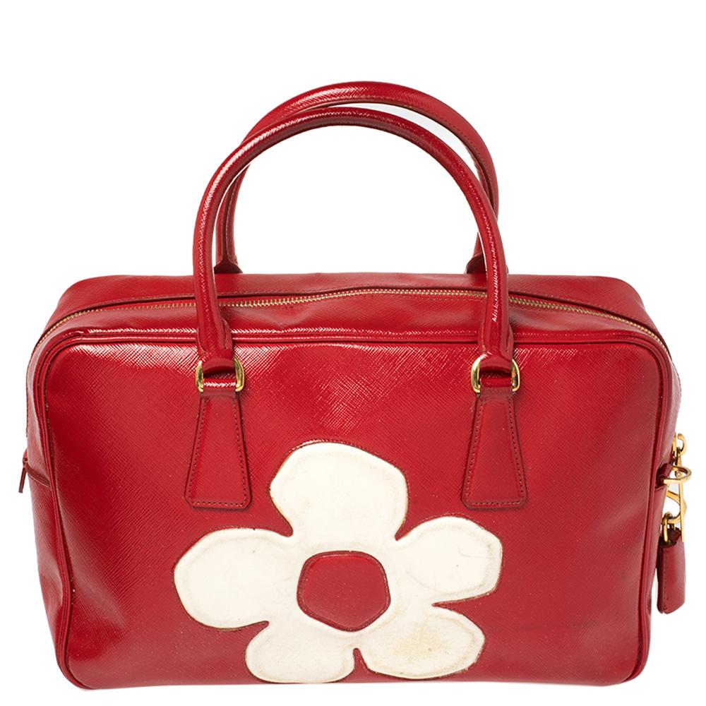 Die Bauletto Bag von Prada ist elegant in ihrer Schlichtheit und Struktur. Sie ist aus Vernice Saffiano-Lackleder gefertigt:: mit einem goldfarbenen Prada-Logo auf der Vorderseite verziert und verfügt über zwei Griffe. Diese elegante Tasche ist