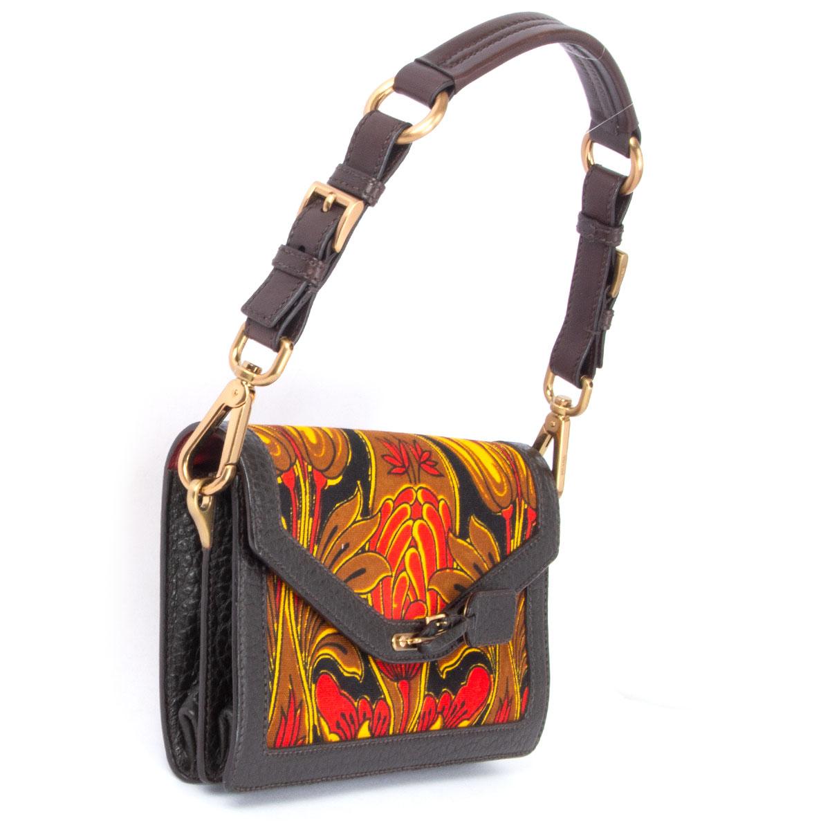 100% authentic Prada shoulder bag in brown, red, yellow and black floral printed canvas featuring espresso brown trimmings and shoulder-strap. Has two decorative buckles on the back. Opens with a magnetic button under the flap and is lined divided