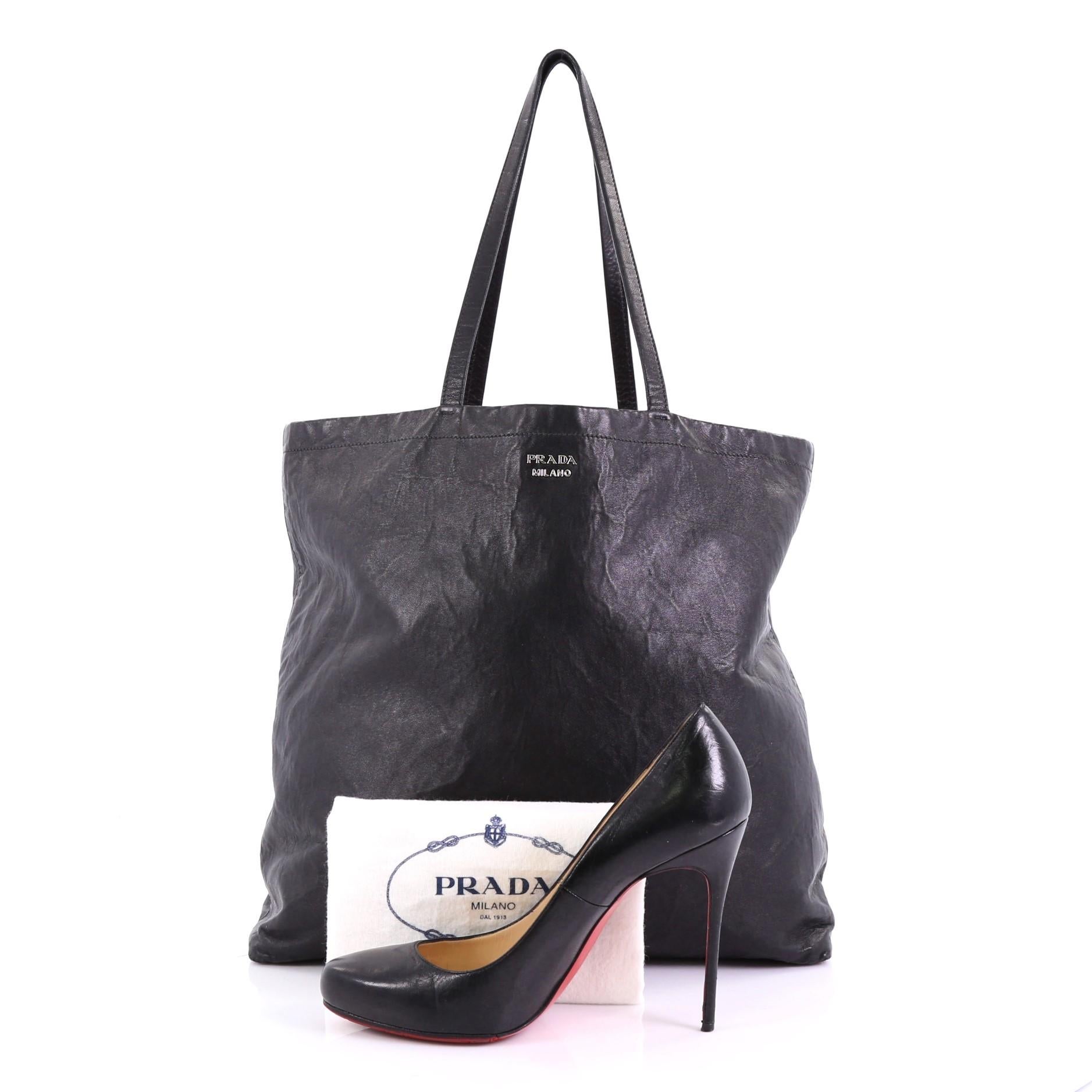 This Prada Reversible Tote Nappa Antique Tall, crafted from black leather, features dual slim leather handles and pink-tone hardware. It opens to a reversible pink leather interior with side zip pocket. **Note: Shoe photographed is used as a sizing