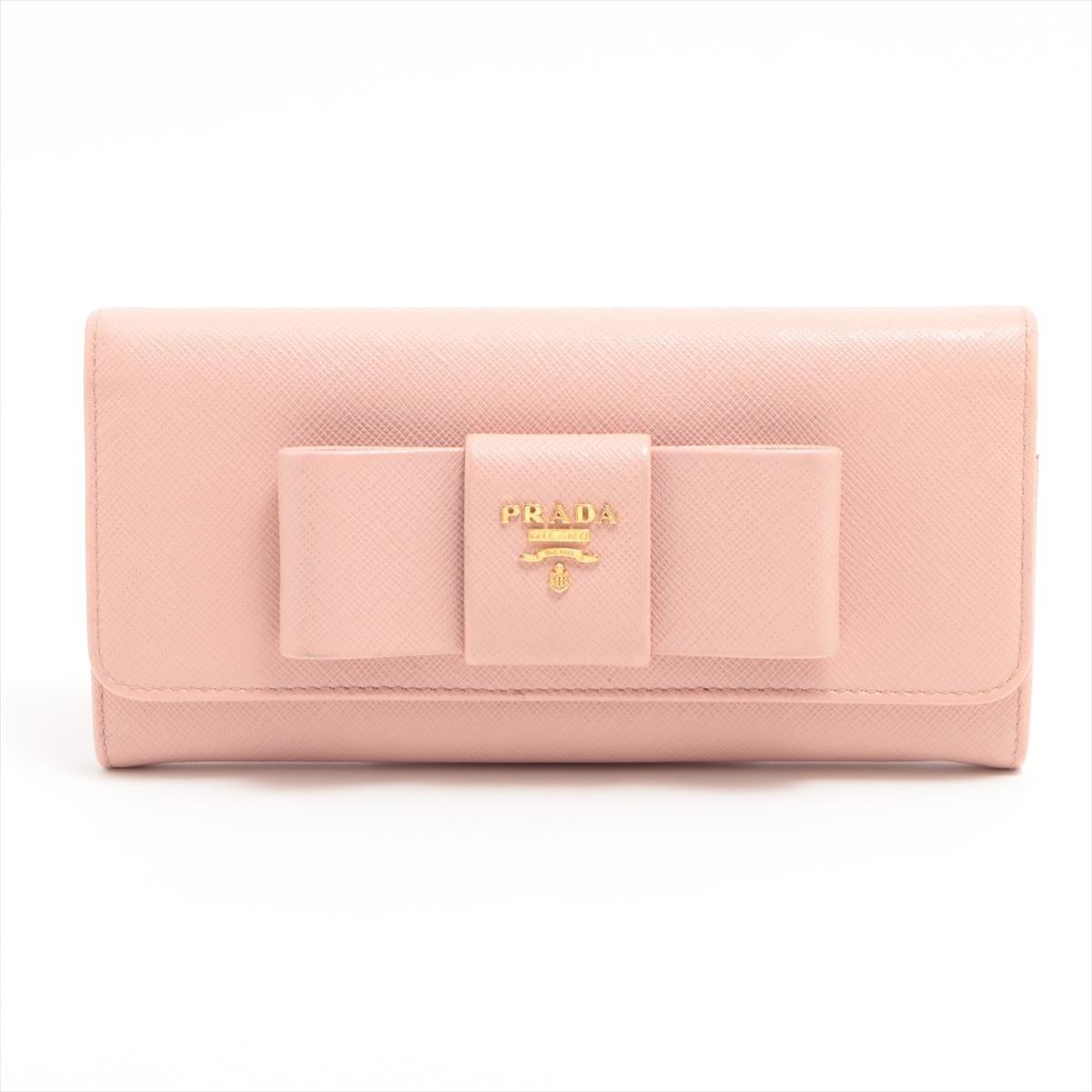 The Prada Ribbon Saffiano Leather Wallet in Pink is a chic and stylish accessory that seamlessly blends luxury with feminine charm. Crafted from Prada's signature Saffiano leather, the wallet features a textured finish that adds a touch of
