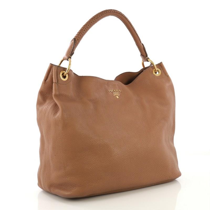 This Prada Rolled Hobo Vitello Daino Large, crafted from brown vitello daino leather, features a single rolled shoulder strap and gold-tone hardware. Its snap closure opens to a brown fabric interior with zip and slip pocket.

Estimated Retail