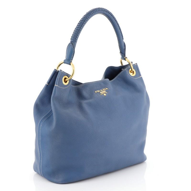 This Prada Rolled Hobo Vitello Daino Large, crafted from blue vitello daino leather, features a single rolled shoulder strap and gold-tone hardware. Its snap closure opens to a blue fabric interior with zip and slip pockets. 

Estimated Retail