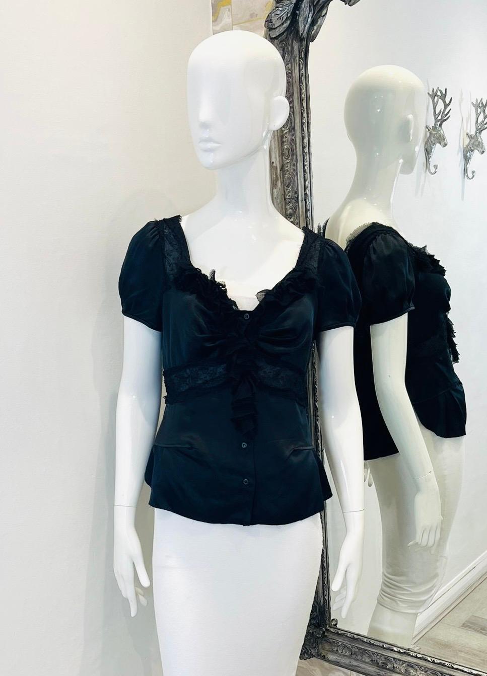 Prada Ruffle & Lace Detailed Silk Top

Black blouse designed with lace inserts and ruffle detailing.

Featuring short, balloon sleeves and drape accented V-Neck.

Styled with centre button fastening and deep, lace trimmed V-Neckline to rear.

Size –