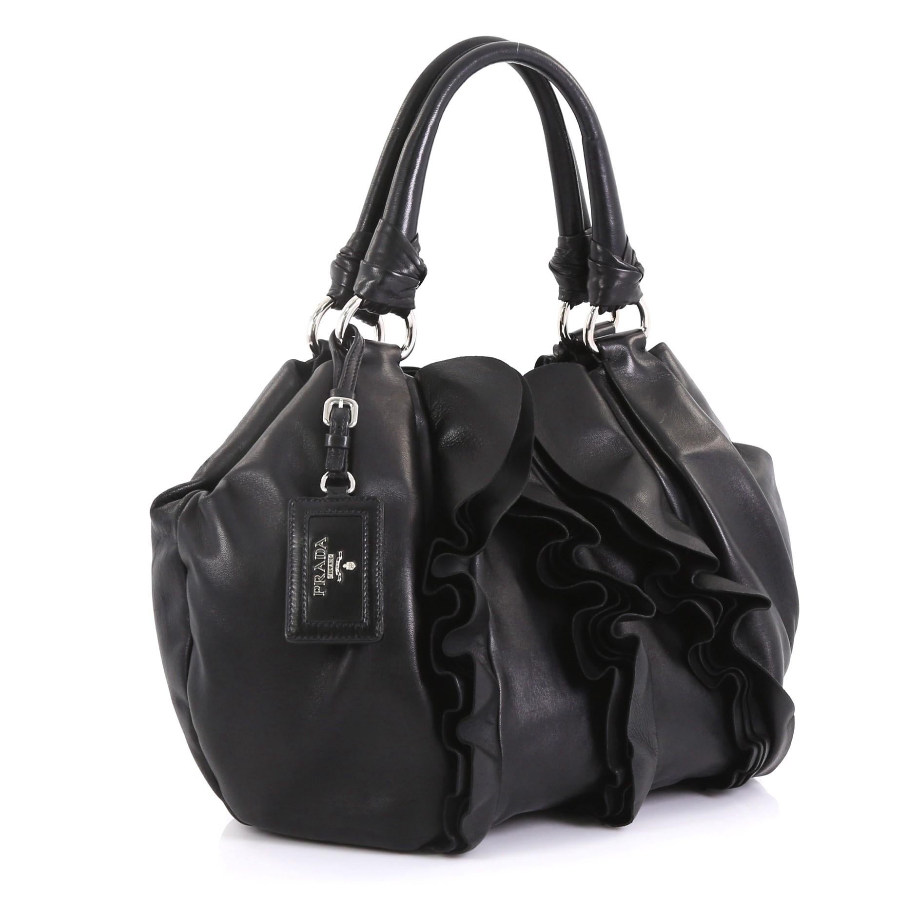 This Prada Ruffle Shoulder Bag Nappa Leather Medium, crafted from black nappa leather, features dual top handles with rings, ruffled and pleated leather accents, and silver-tone hardware. Its magnetic snap button closure opens to a black fabric