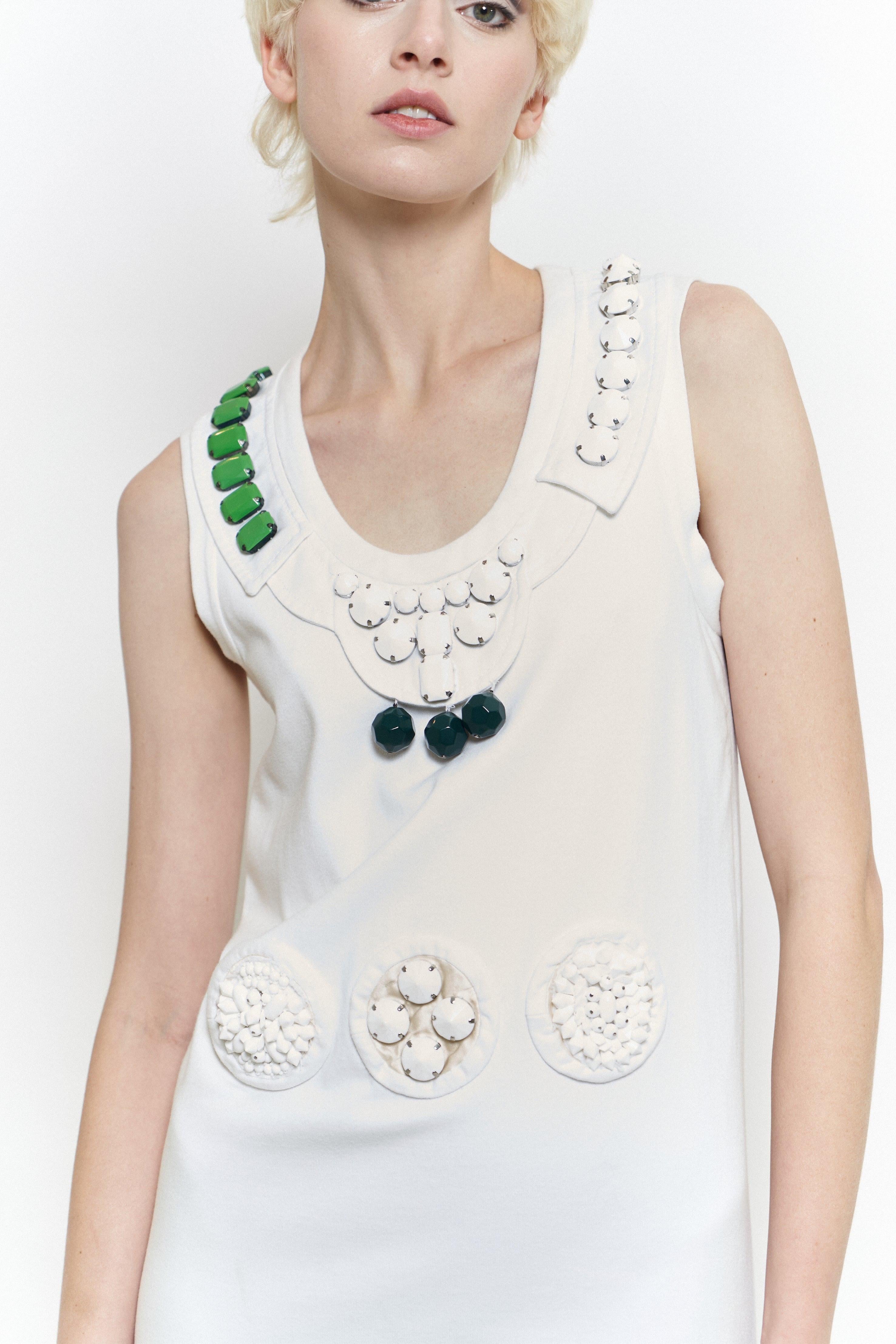 Dating to the S/S 2003 collection, this Prada dress was look 39 on the runway. A shift style crafted from heavy white cotton, this features a scoop neck & is embellished with chunky matte jewels & beads at the neckline, waist & bottom hem. A