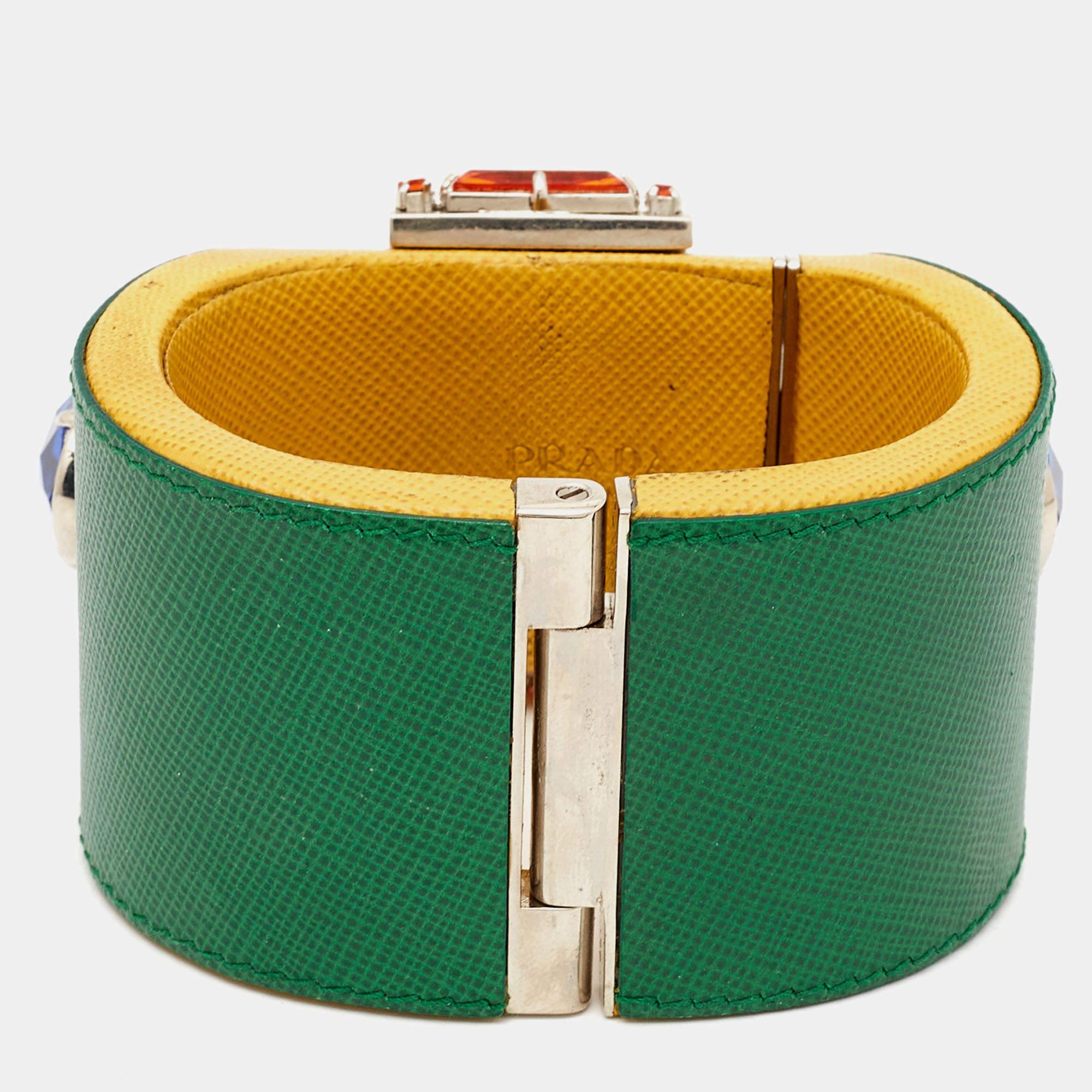 Réalisé avec une attention méticuleuse aux détails, le bracelet Prada exsude un luxe raffiné. Le cuir souple, orné de cristaux scintillants, est élégamment complété par la quincaillerie épurée de couleur argentée. Cet accessoire allie