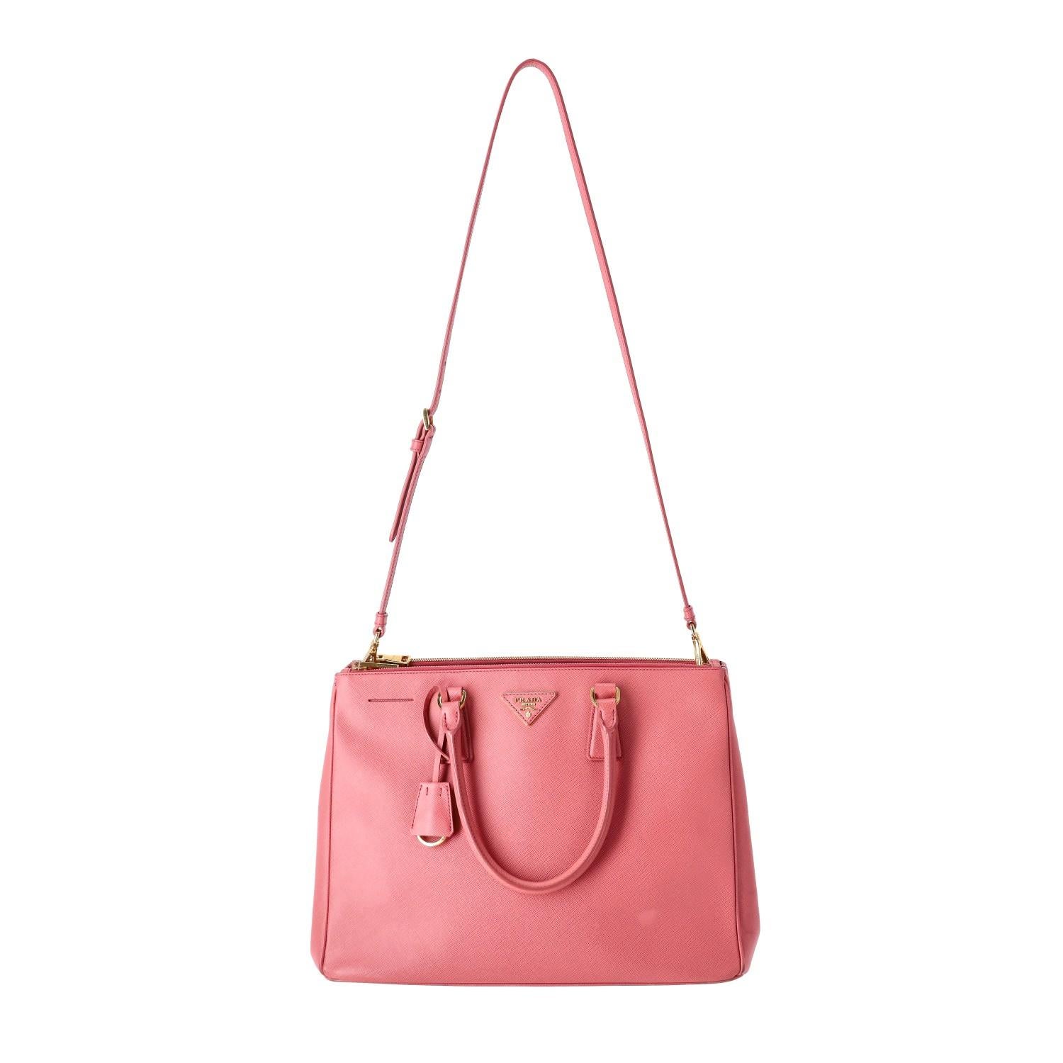 Prada Saffiano Leather Double Zip Galleria Tote Bag

Pink tote bag crafted in Saffiano gross-grain leather.

Detailed with signature 'Prada' triangle logo to the centre, gold hardware and leather clochette.

Featuring rolled top handles and
