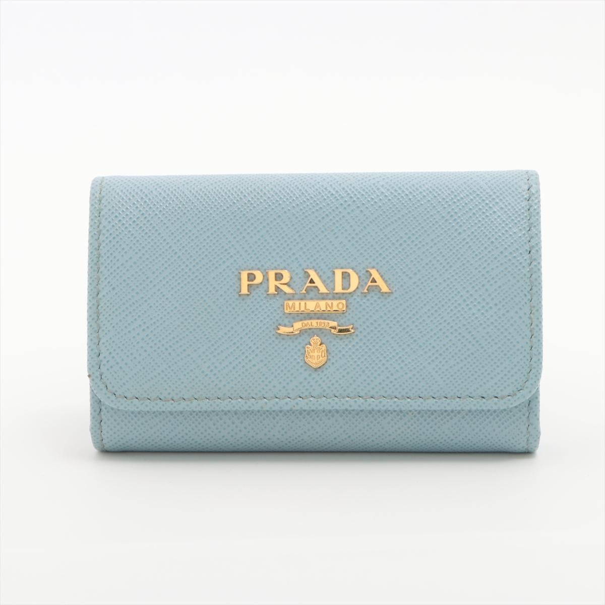 The Prada Saffiano Leather Key Case in sky blue is a sleek and functional accessory that combines style with practicality. Made from Prada's signature Saffiano leather, known for its durability and textured finish, the key case features a bright sky