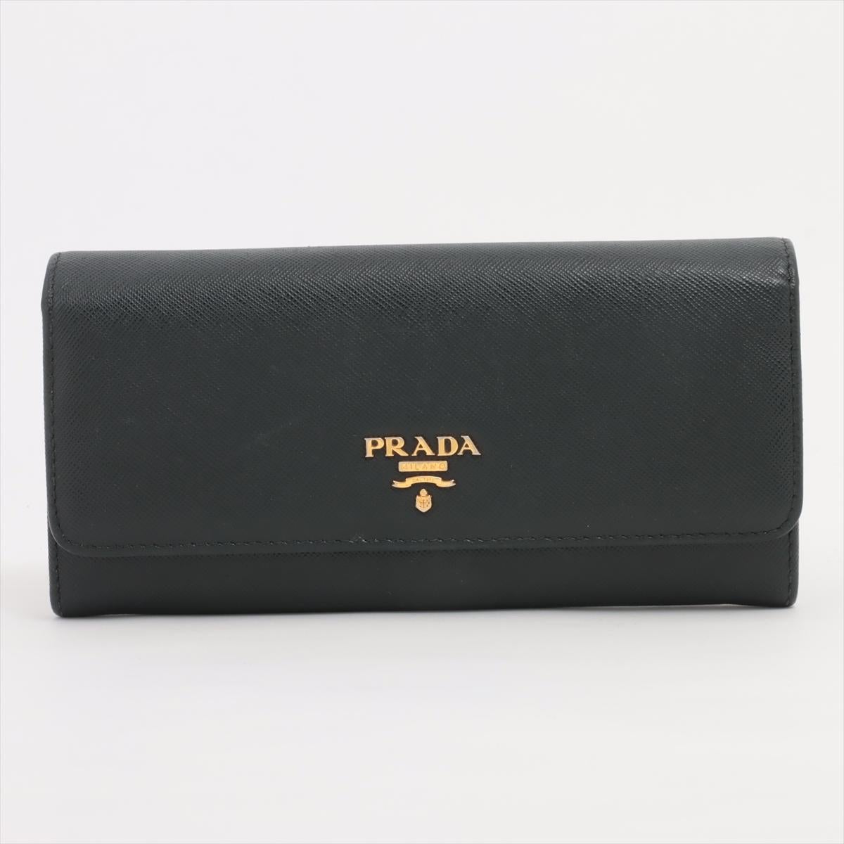 The Prada Saffiano Leather Long Wallet in Black is a sophisticated and timeless accessory crafted from high-quality Saffiano leather. Renowned for its durability and distinctive crosshatch texture, Saffiano leather adds a luxurious touch to the
